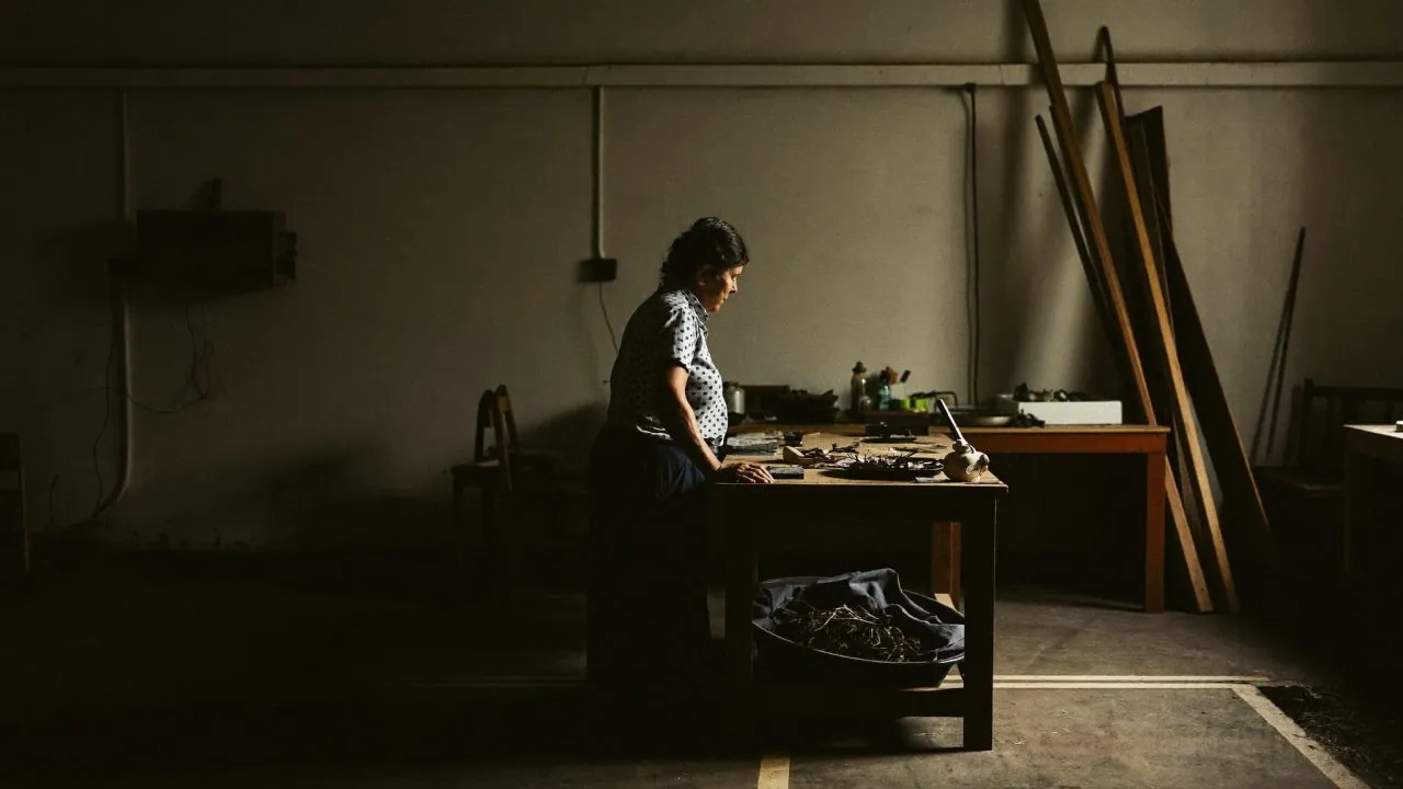 An owner working alone at a bench in a dim workshop